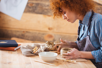 Redhead attractive young woman creating an earthen jar
